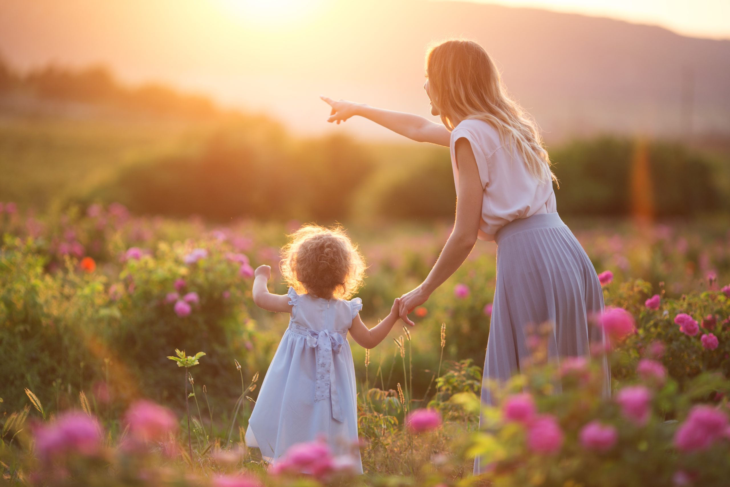 Mother and young daughter roaming a sunny meadow