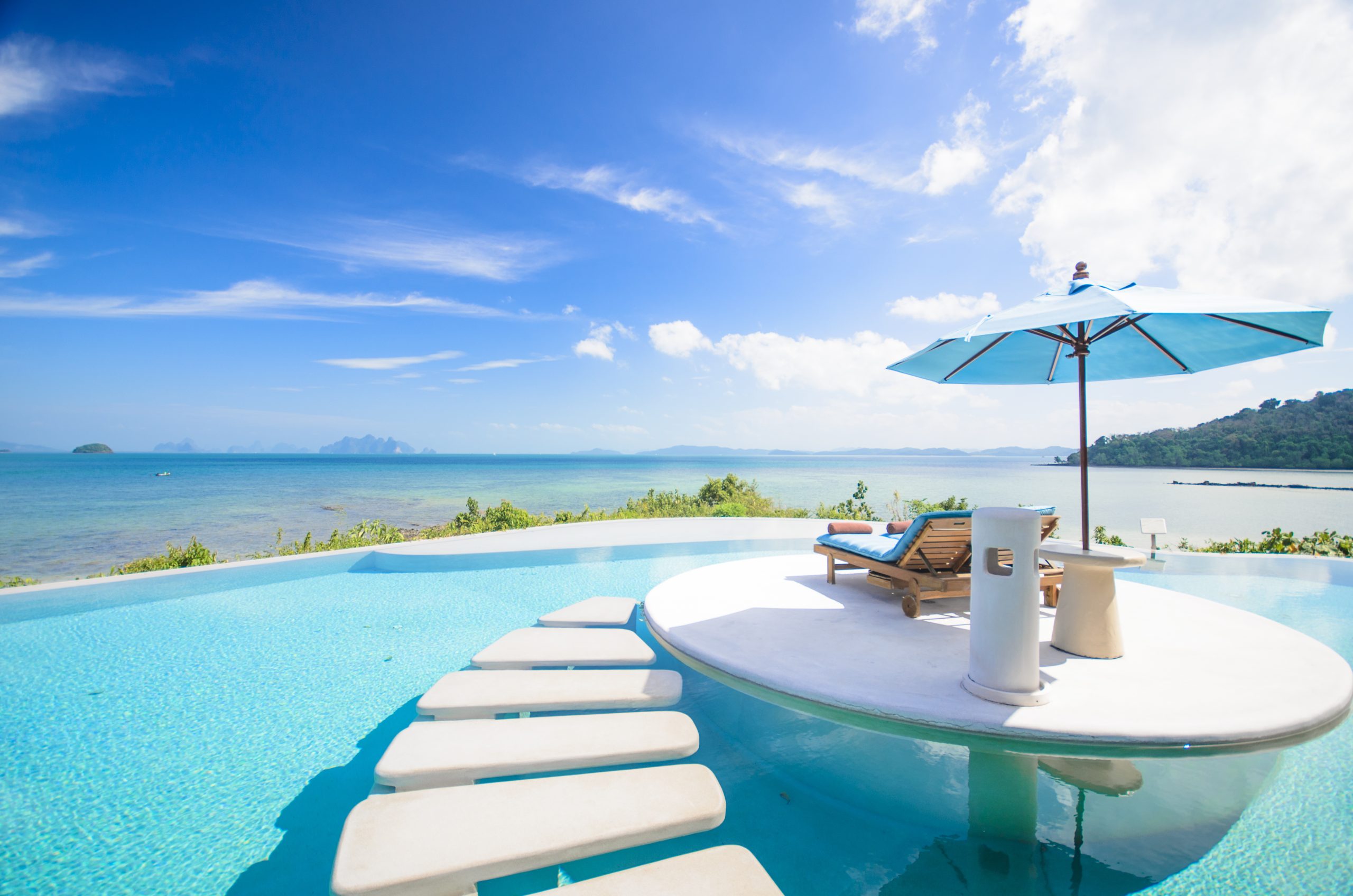 swimming pool with table, parasol and a chaise lounge 